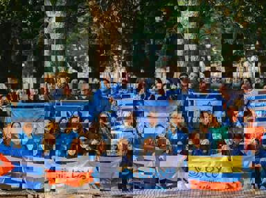 Una multitud diversa de personas celebrando en un concierto, levantando las manos y vitoreando.