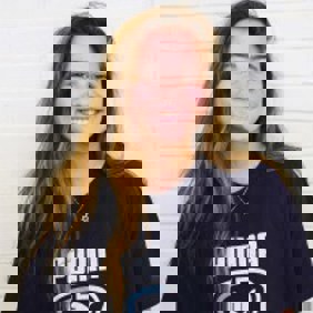 Un grupo diverso de jóvenes adultos saltando de emoción en un frondoso jardín verde durante un evento comunitario.