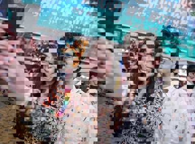 Una multitud diversa de personas celebrando en un concierto, levantando las manos y vitoreando.